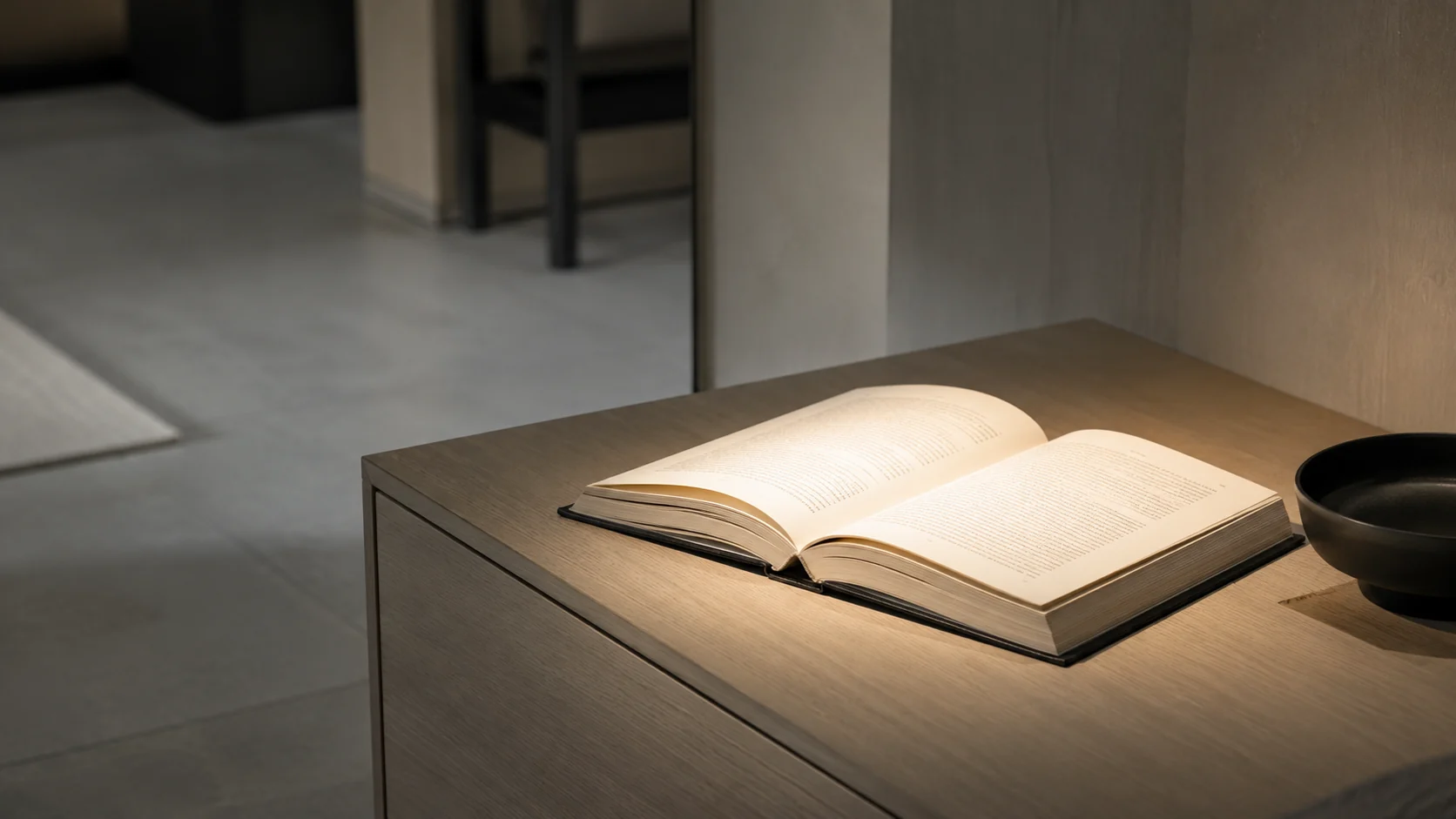 開いた本の面を手元灯が読みやすい明るさで照らし、周辺も柔らかく保った照度バランスの近景