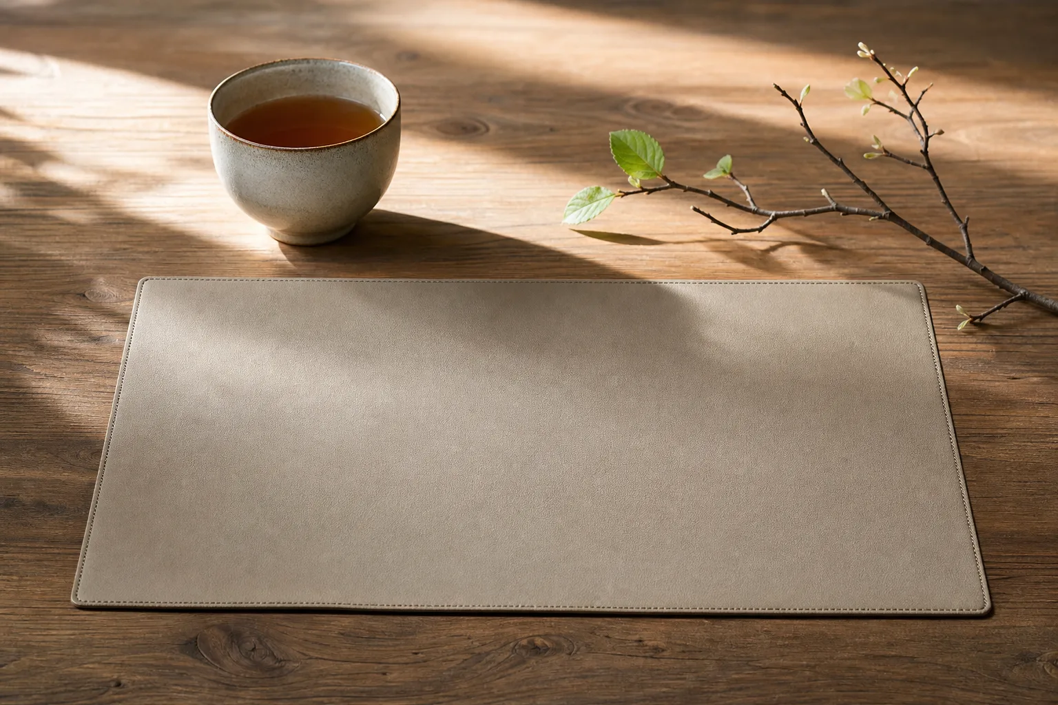 木のデスクに置かれた茶と芽吹きの枝。買い時を見極める季節感の静物